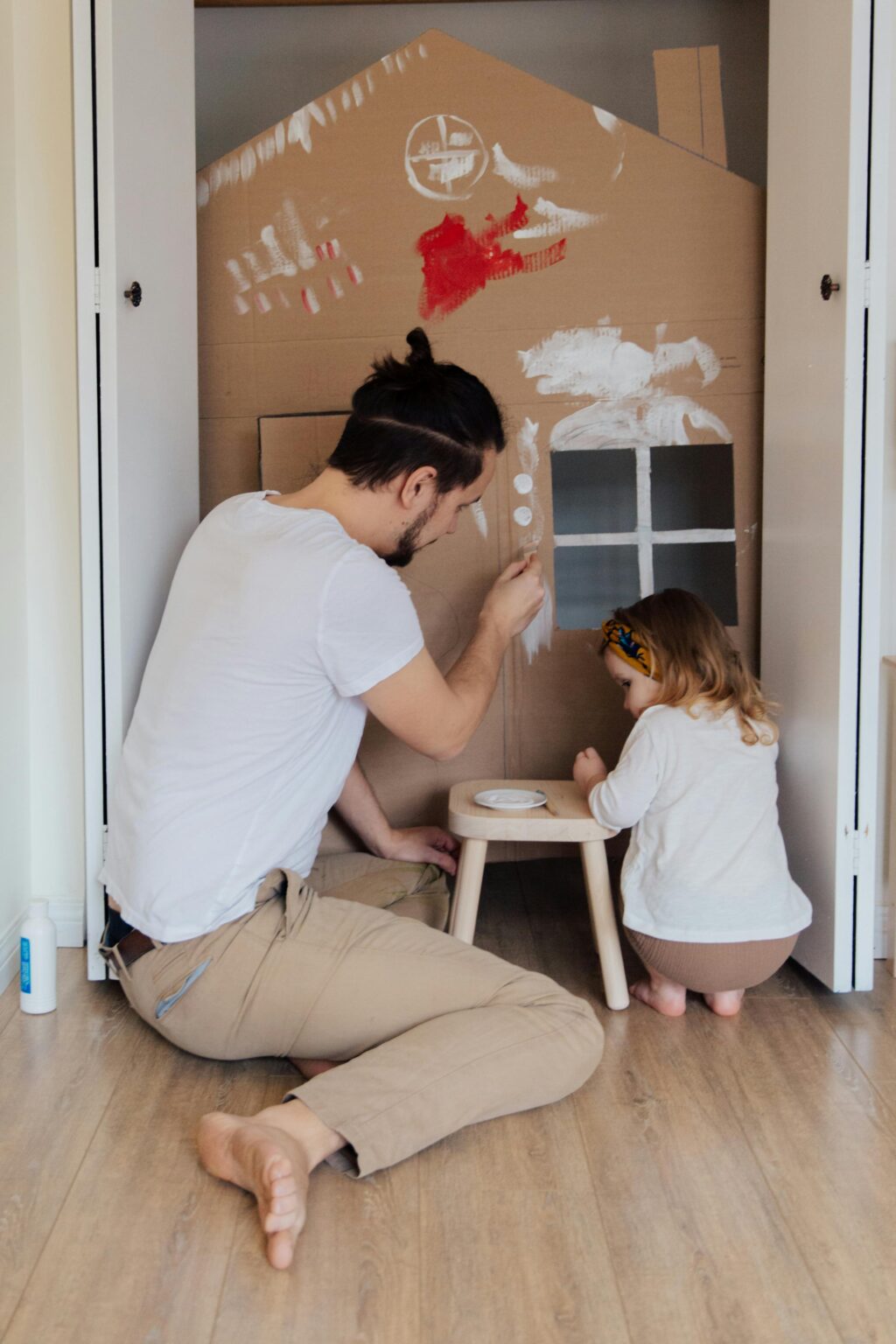 Dad and daughter painting cardboard house