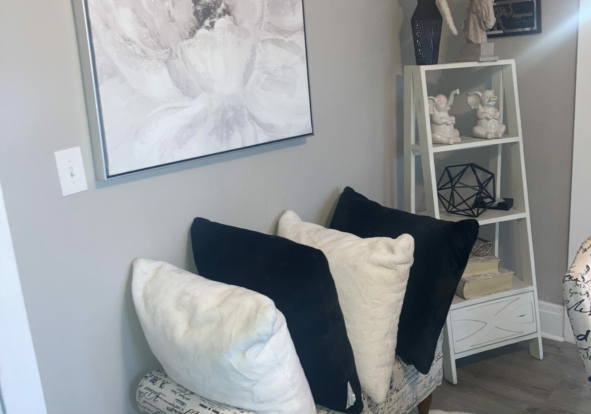 Bench with throw pillows and decorated bookshelf and flower photo on the wall